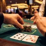 Player doubling down in blackjack with 6 and 5 cards showing 11, placing additional chips and signaling with one finger